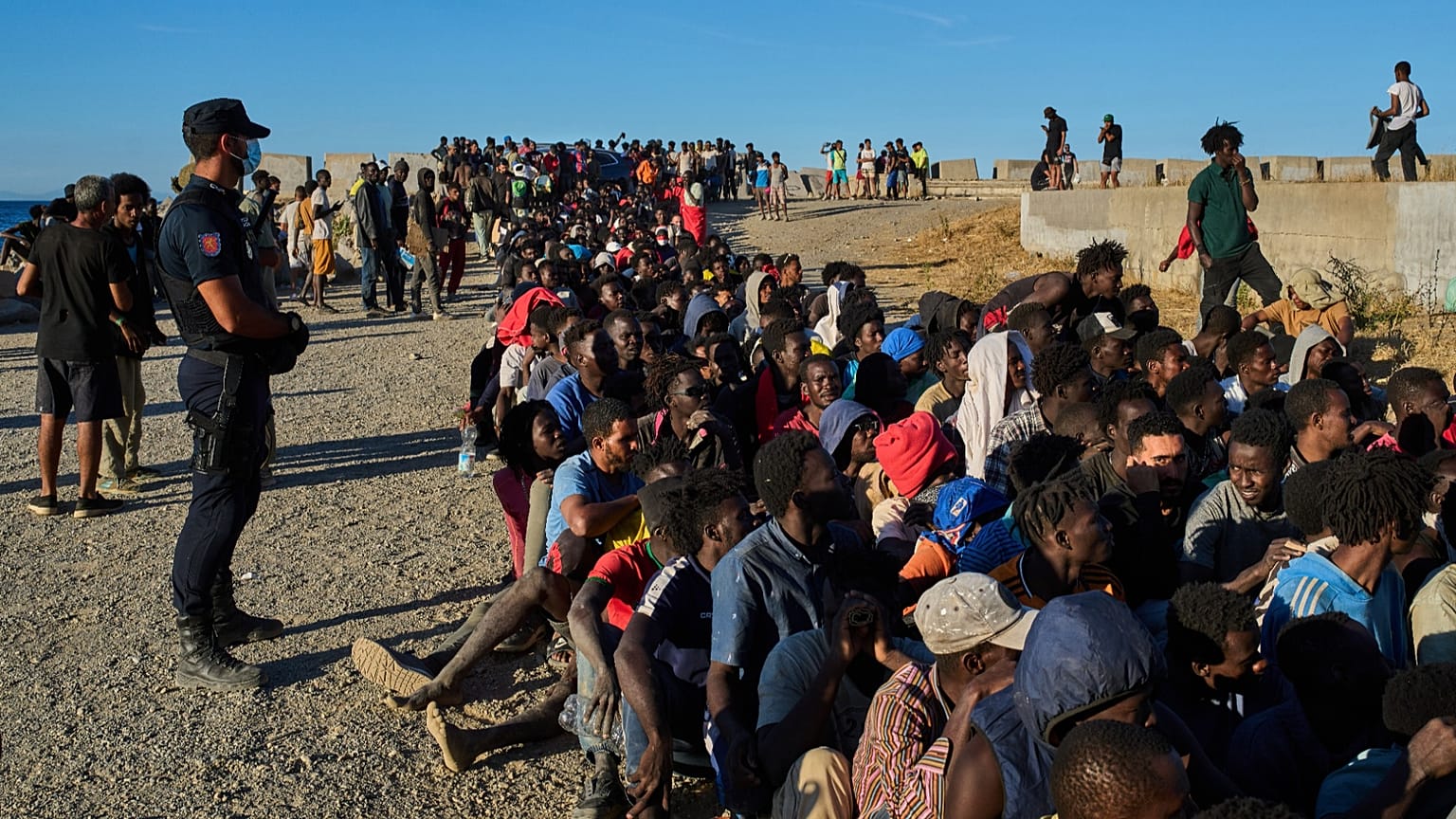 ARCHIVO: Migrantes que cruzaron de Marruecos a España hacen fila para recibir alimentos en una playa del enclave español de Ceuta, el lunes 3 de agosto de 2026