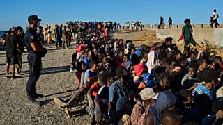 ARCHIVO: Migrantes que cruzaron de Marruecos a España hacen fila para recibir alimentos en una playa del enclave español de Ceuta, el lunes 3 de agosto de 2026