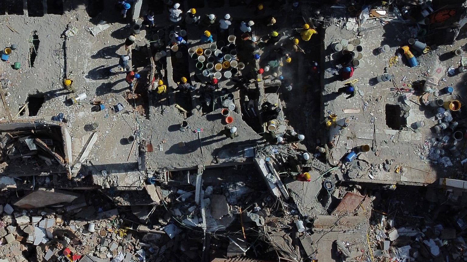 Volunteers and rescue workers use buckets to remove debris of a collapsed building a day after an earthquake struck Cali, 11 August, 2026