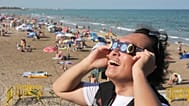 A man wears special eclipse glasses before a total solar eclipse set to begin around sunset at a beach near Valencia, 12 August, 2026
