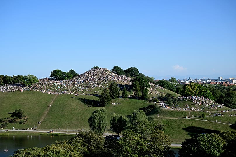 People gather at the Olympiaberg in Munich's Olympiapark to watch the partial solar eclipse, 12 August, 2026