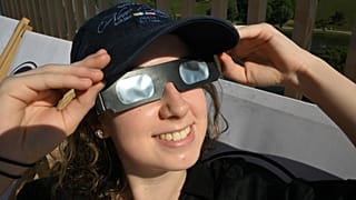 Une jeune femme observe le soleil avec des lunettes homologuées