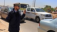 یک مامور پلیس در ساعت اوج ترافیک در بنغازی لیبی خودروها را از یک ایست بازرسی عبور می‌دهد ۲ مه ۲۰۱۹