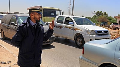 Bir polis memuru, Libya'nın Bingazi kentinde 2 Mayıs 2019'da yoğun saatlerde bir kontrol noktasında araçları geçmeleri için işaret ediyor.