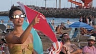 A beachgoer wearing special eclipse glasses points skyward before the partial phase of the solar eclipse at Puerto de Sagunto beach near Valencia