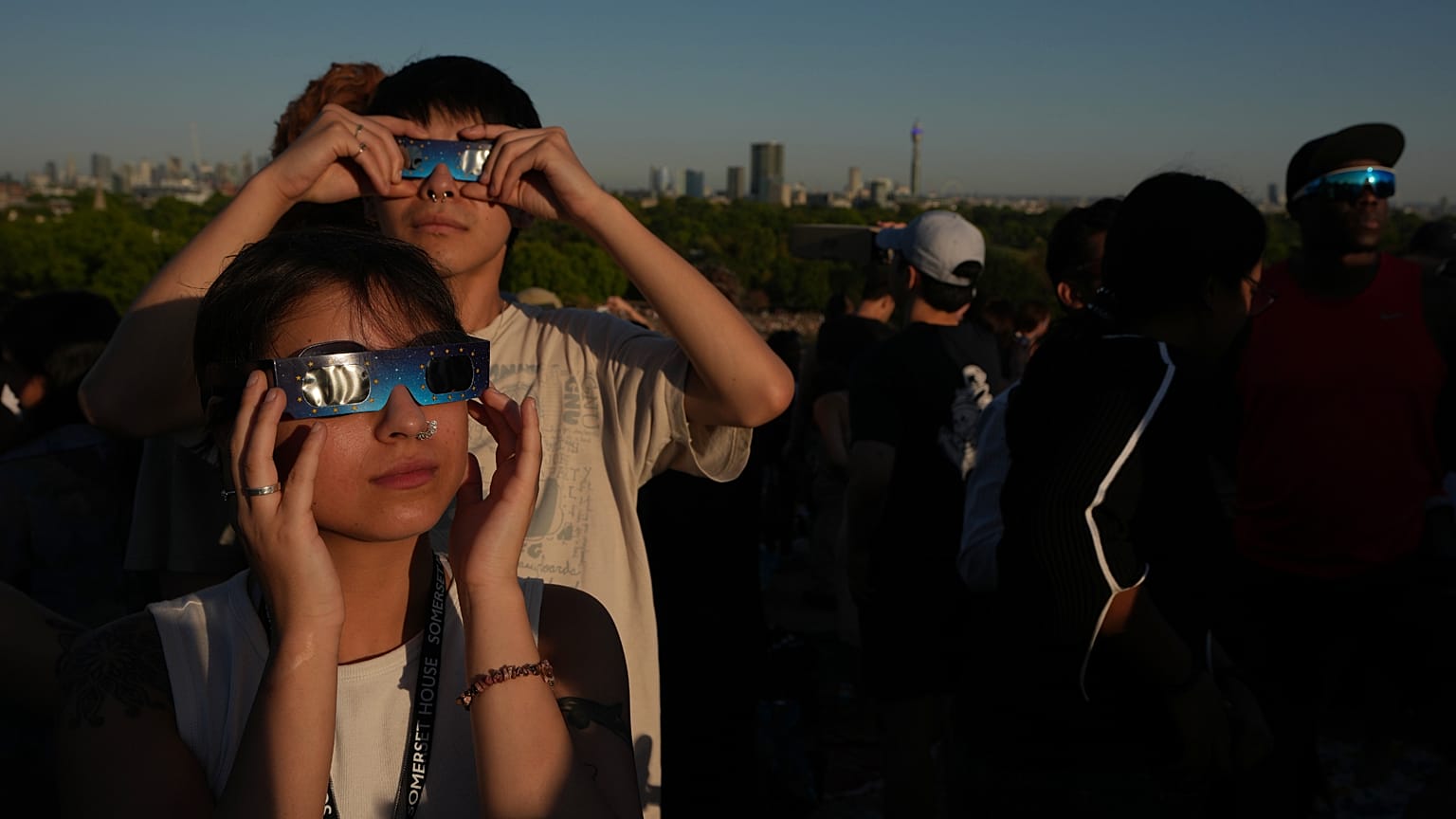 Des personnes observent l'éclipse solaire depuis Primrose Hill, à Londres, mercredi 12 août 2026. (Photo AP/Kirsty Wigglesworth)