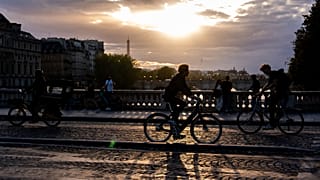 Des cyclistes circulent sur un pont enjambant la Seine au coucher du soleil, ce jeudi 28 août 2025, à Paris.