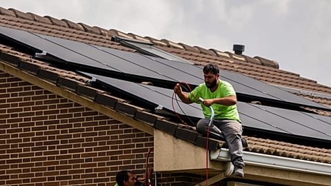 In this September 2022 file photo, a worker installs solar panels on the roof of a house in Rivas-Vaciamadrid, Spain.