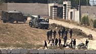 جنود إسرائيليون يقفون للحراسة إلى جانب مستوطنين أمام منازل فلسطينية فرضوا عليها حصاراً في قرية قصرة، جنوب نابلس، في الضفة الغربية المحتلة