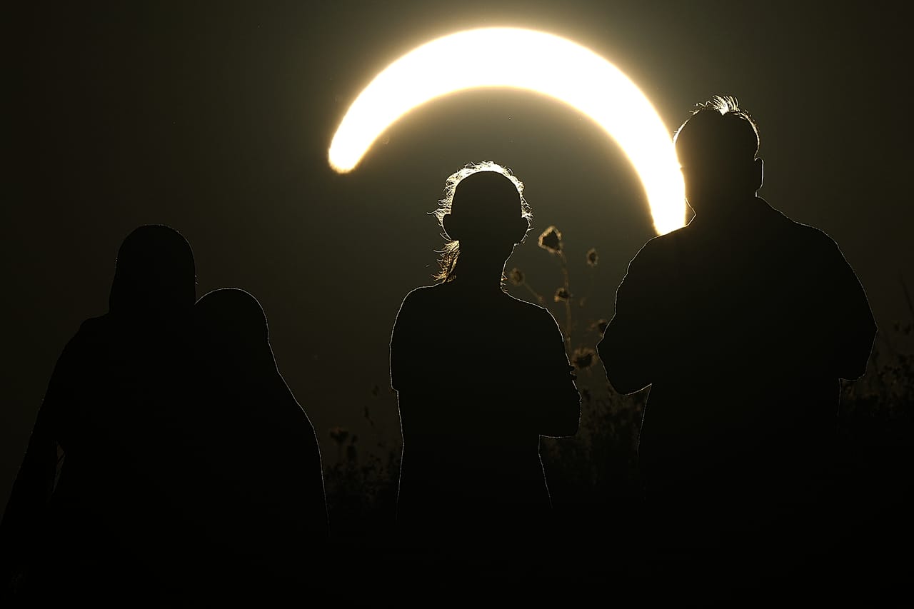 Menschen beobachten eine partielle Sonnenfinsternis in Northala Fields in London