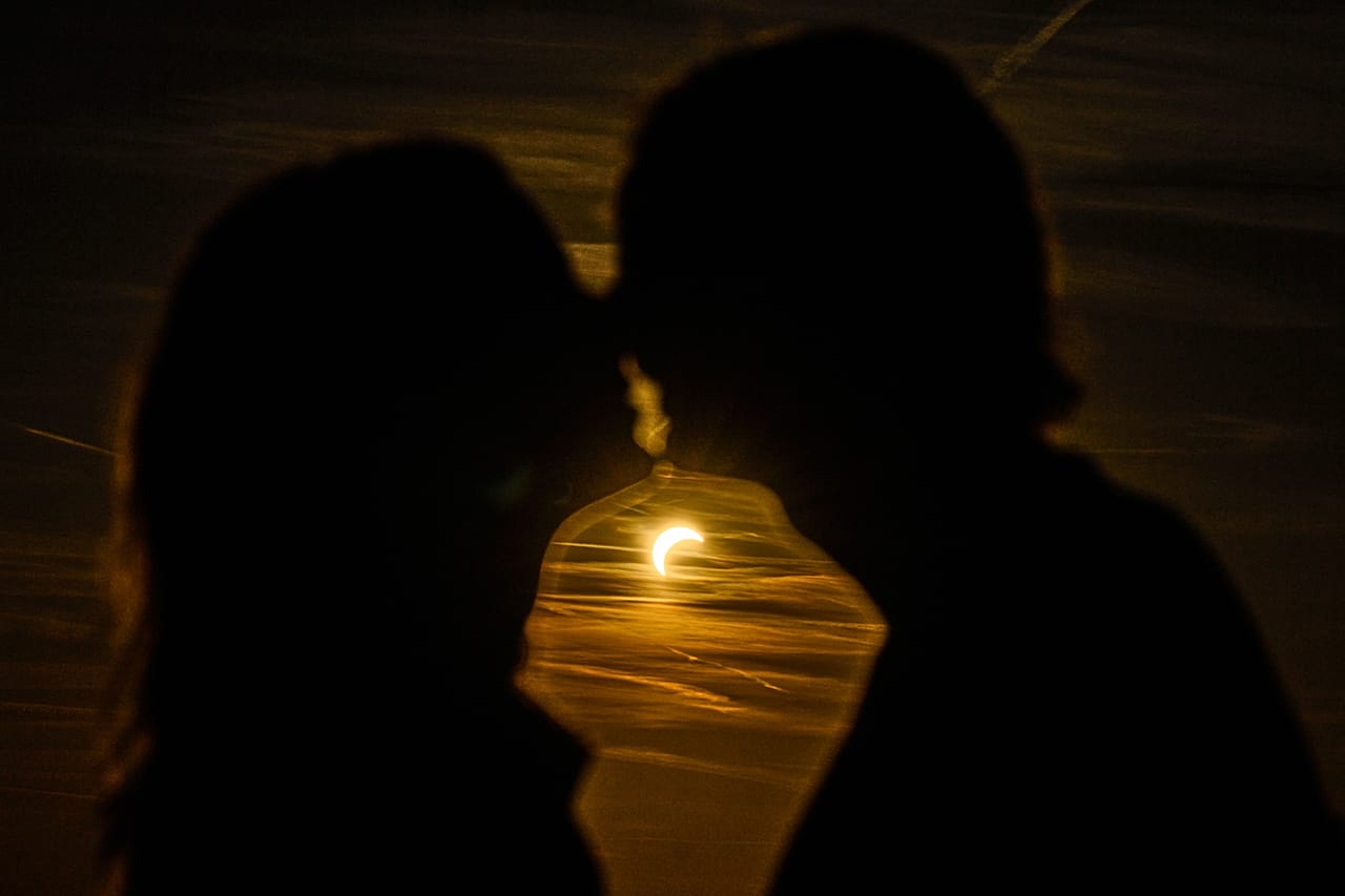 Ein Paar küsst sich während der partiellen Sonnenfinsternis auf dem Gelände des ehemaligen Flughafens Tempelhof in Berlin in Deutschland