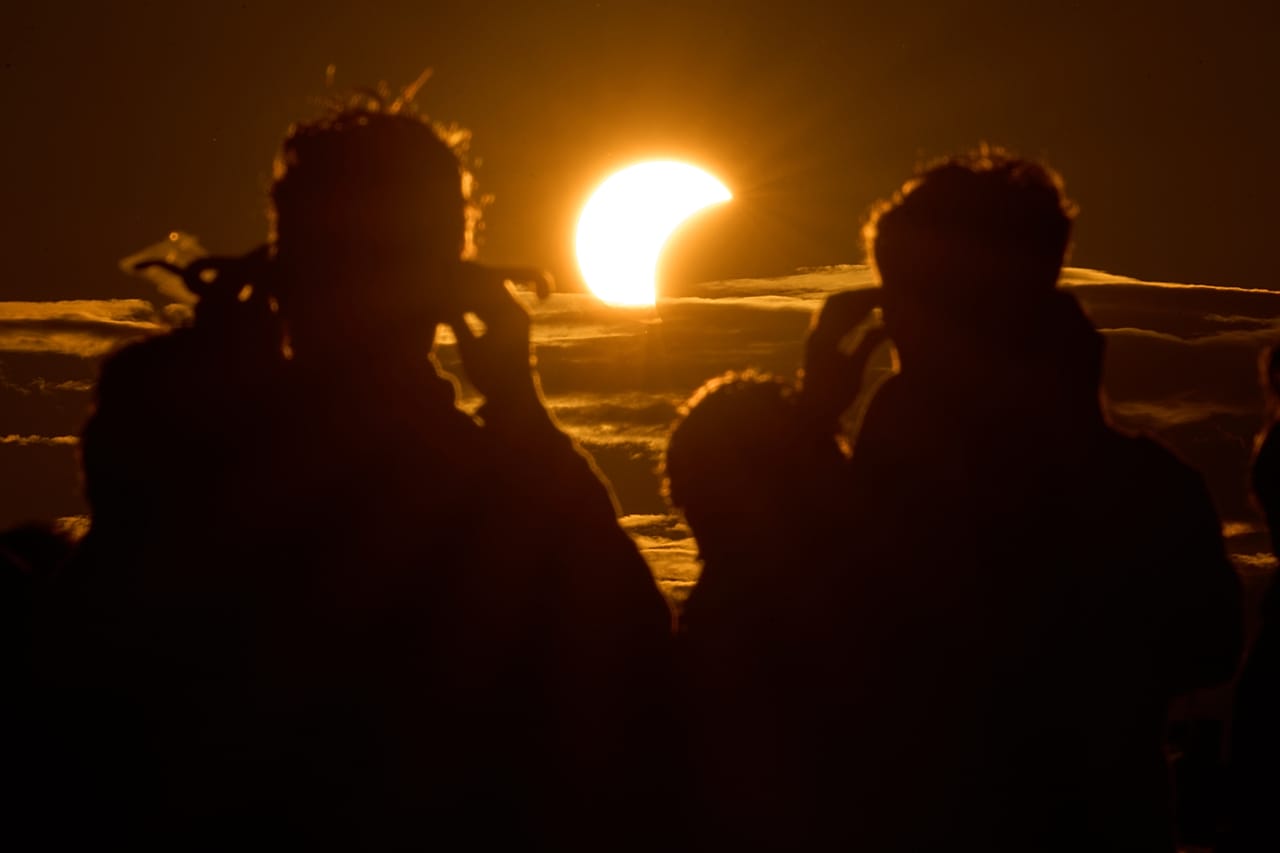 Menschen beobachten eine Sonnenfinsternis am Ufer des Finnischen Meerbusens in Sankt Petersburg in Russland