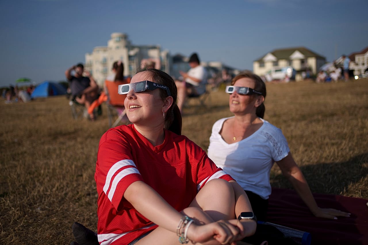 Menschen beobachten mit Schutzbrillen eine partielle Sonnenfinsternis am Crosby Beach in Liverpool, wo der Mond mehr als 90 Prozent der Sonne verdeckt