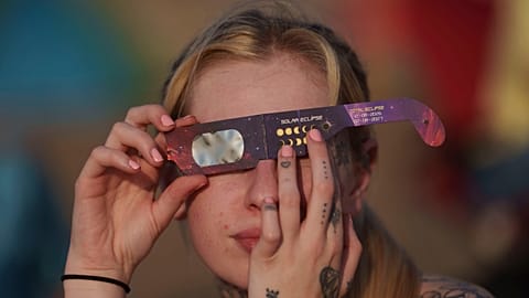 A person observes a partial solar eclipse with special protective glasses at Crosby beach in Liverpool as the moon covers part of the sun in Liverpool, England