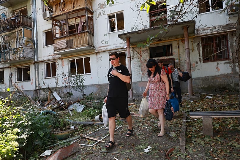 Residents leave their damaged home after a Russian air guided bomb strike in Zaporizhzhia, Ukraine, Monday, Aug. 10, 2026.