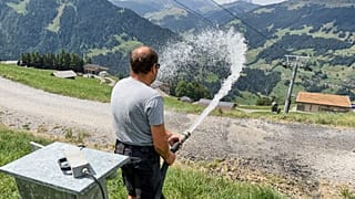 Juerg Klopfenstein, responsible for snowmaking operations at Adelboden-Lenk ski Resort, waters a road alongside ski slopes in Lenk valley, Switzerland, Aug. 3, 2026. 