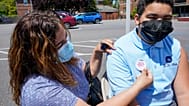 Kendy Marte, left, places a sticker on her son Stanley Pena, 13, after he was inoculated with the first dose of the Pfizer COVID-19 vaccine in New York.