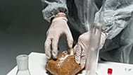 Trabajador de laboratorio analiza sustancia en polvo en un entorno de laboratorio utilizando equipo de seguridad.