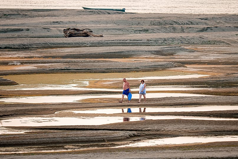 People walk on a sandbank on the Danube as usually submerged areas are exposed amid exceptionally low water levels in Rasova, 7 August, 2026