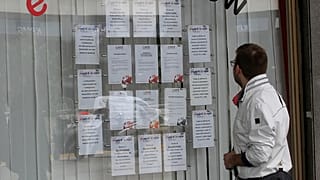 صورة أرشيفية: في هذه الصورة التي التقطت يوم الاثنين، 2 أبريل 2012، ينظر شاب إلى إعلان وظيفة معروض في واجهة مكتب توظيف في ميلانو بإيطاليا