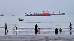 People on the beach as commercial vessels are anchored in the Strait of Hormuz off Bandar Abbas, 5 August, 2026