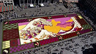 Vue d'ensemble d'un immense tapis de fleurs inspiré de "La Grande Vague de Kanagawa" de l'artiste japonais Katsushika Hokusai, sur la Grand-Place historique de Bruxelles