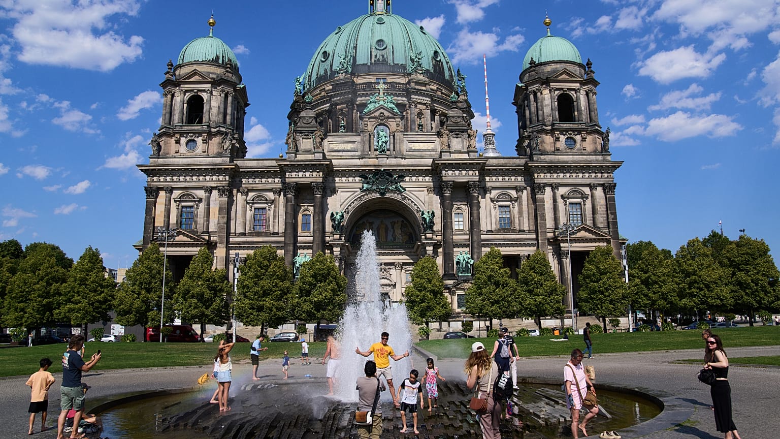Angesichts steigender Temperaturen in Berlin erfrischen sich Menschen am Donnerstag, dem 30. Juli 2026, in einem Springbrunnen vor dem Dom. (AP Photo/Ebrahim Noroozi)