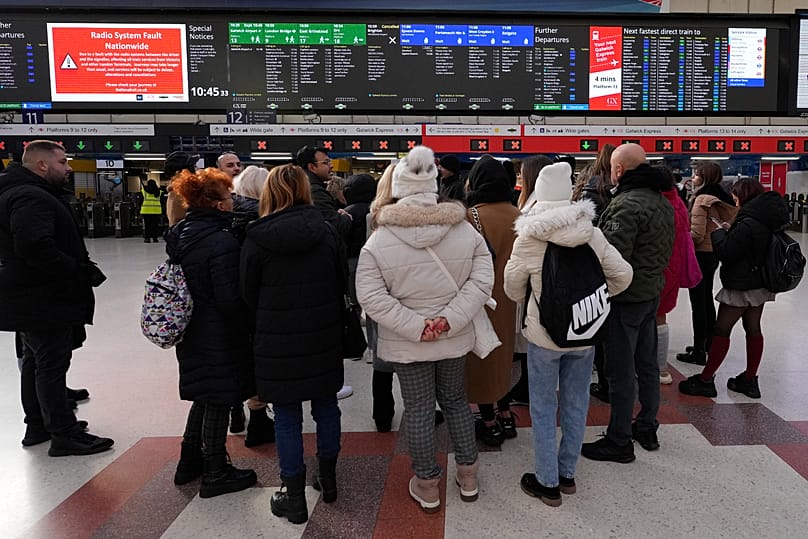 Travellers look at the information board at Victoria Station in London, 6 December, 2024