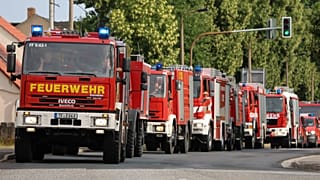 Symbolbild: Feuerwehrleute am  26. Juli 2022 in einem Konvoi am Ort eines Waldbrands in der Nähe von Falkenberg in Deutschland