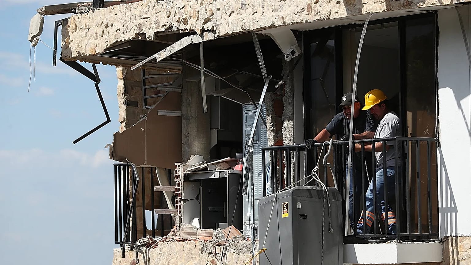 Tres días después del terremoto que azotó Cali, Colombia, el jueves 13 de agosto de 2026, varias personas retiran una lavadora de una casa dañada