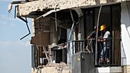 Tres días después del terremoto que azotó Cali, Colombia, el jueves 13 de agosto de 2026, varias personas retiran una lavadora de una casa dañada
