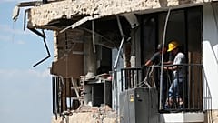 Tres días después del terremoto que azotó Cali, Colombia, el jueves 13 de agosto de 2026, varias personas retiran una lavadora de una casa dañada