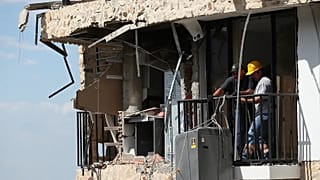 Tres días después del terremoto que azotó Cali, Colombia, el jueves 13 de agosto de 2026, varias personas retiran una lavadora de una casa dañada