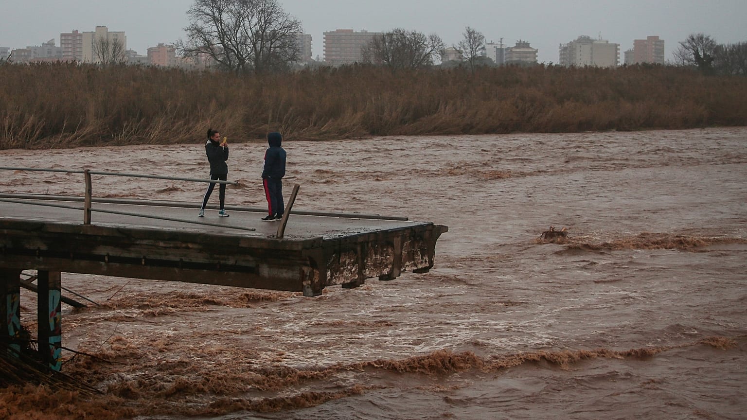 En una foto de archivo de 2020, dos personas echan fotos desde lo alto de un puente derrumbado en Malgrat, cerca de Barcelona, ​​España