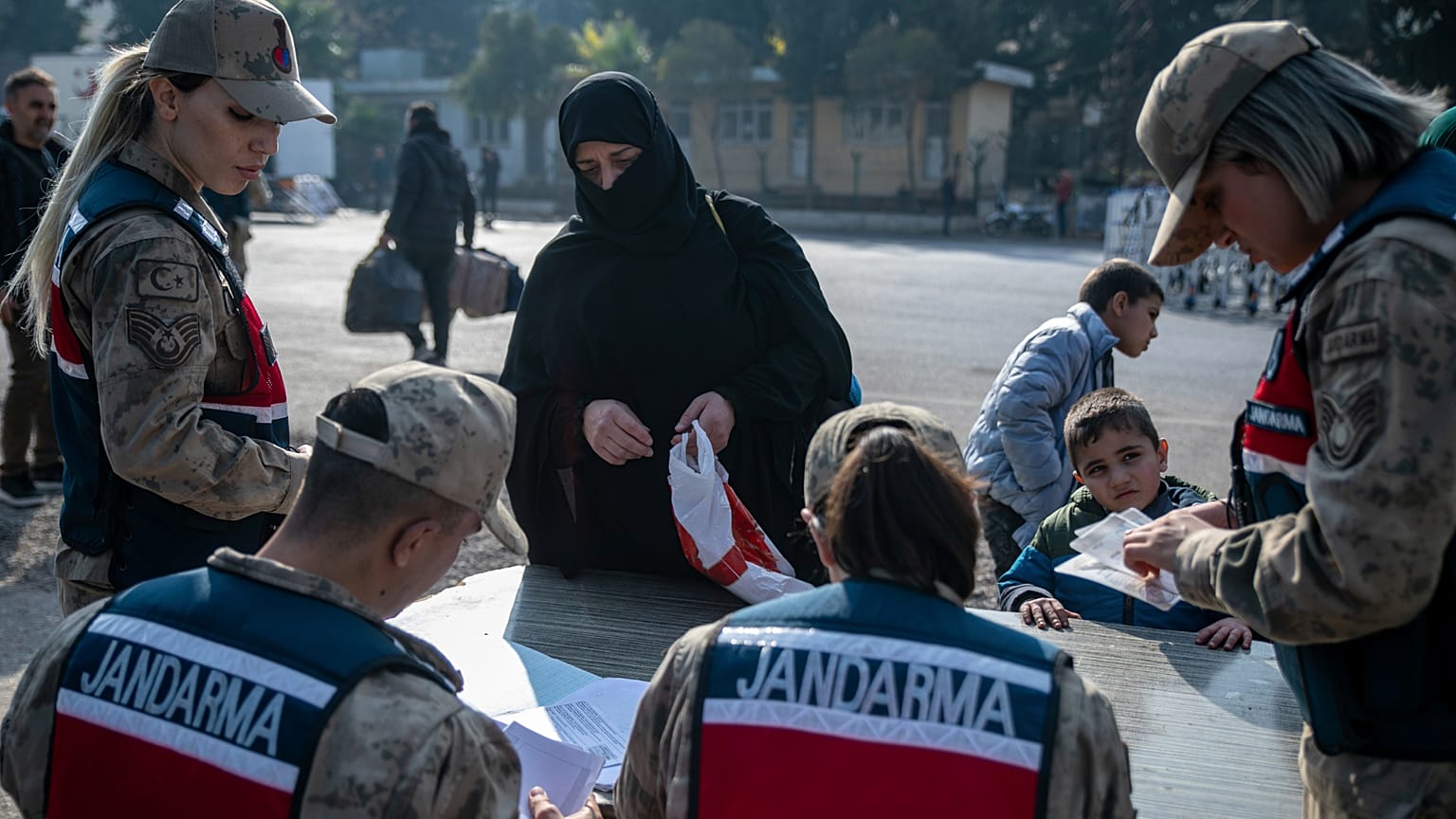 امرأة سورية تسلّم وثائقها لعناصر الدرك التركي أثناء عبورها من تركيا إلى سوريا عبر معبر "جيلفي غوزو" الحدودي بالقرب من أنطاكية، جنوبي تركيا