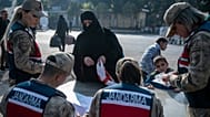 امرأة سورية تسلّم وثائقها لعناصر الدرك التركي أثناء عبورها من تركيا إلى سوريا عبر معبر "جيلفي غوزو" الحدودي بالقرب من أنطاكية، جنوبي تركيا
