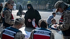 امرأة سورية تسلّم وثائقها لعناصر الدرك التركي أثناء عبورها من تركيا إلى سوريا عبر معبر "جيلفي غوزو" الحدودي بالقرب من أنطاكية، جنوبي تركيا