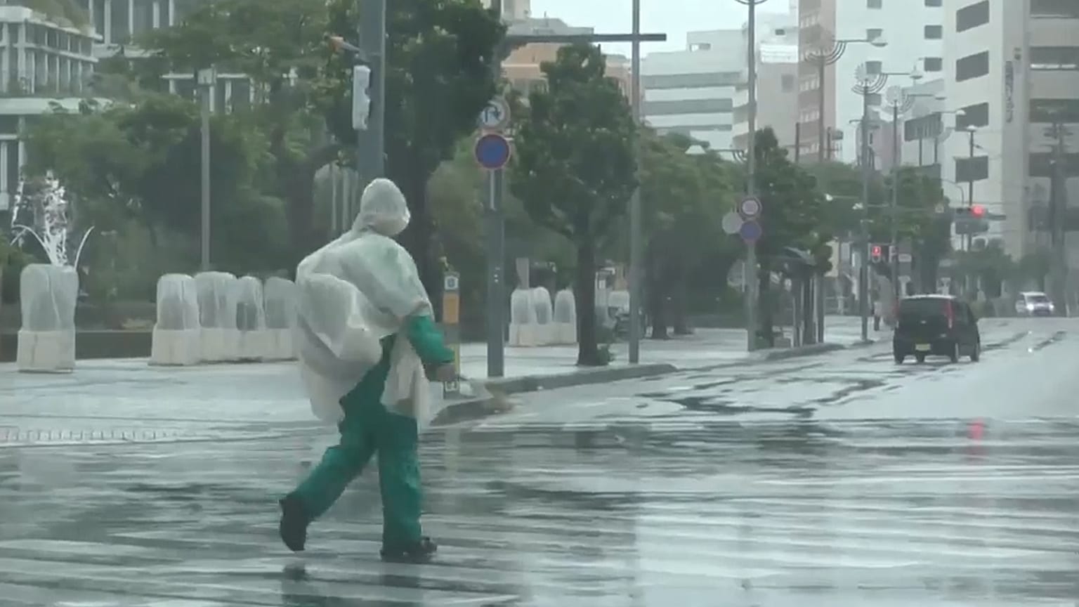 في هذه الصورة المأخوذة من فيديو قدمته قناة NTV-NNN، يظهر شخص يسير تحت المطر بينما يقترب إعصار دولفين من المدينة، في ناها، اليابان، يوم الجمعة 7 أغسطس 2026. (NTV-NNN عبر AP)
