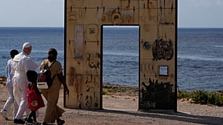 Pope Leo XIV walks together with a migrant family at the Gateway of Europe monument in Lampedusa, Sicily, southern Italy, Saturday, July 4, 2026