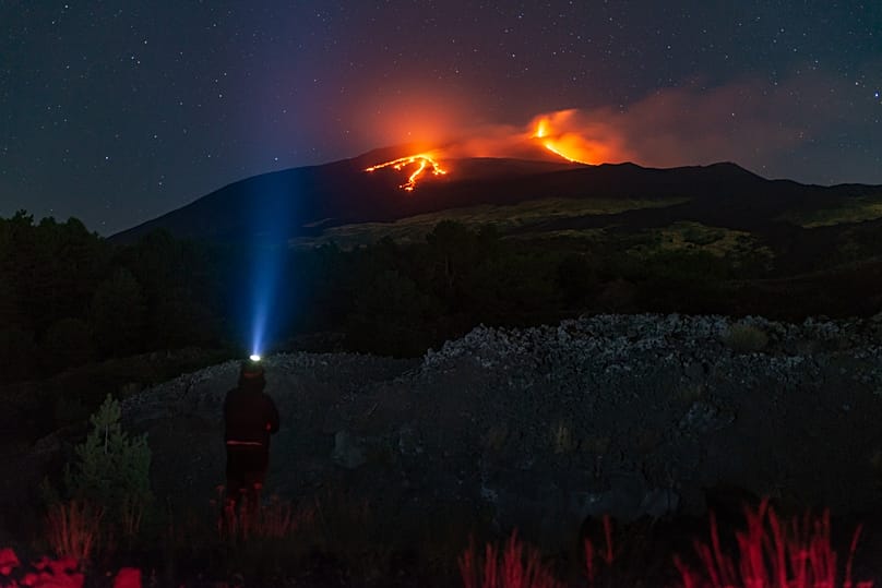 A atividade eruptiva mantém‑se no Etna, onde duas correntes de lava continuam a descer pelas encostas do vulcão, vista de Nicolosi, perto de Catânia, Itália, 26 de agosto de 2025. 