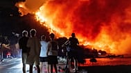Varias personas observan un incendio forestal en la costa adriática cerca de Omis, en el sur de Croacia, la madrugada del viernes 14 de agosto de 2026.
