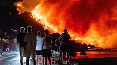 Varias personas observan un incendio forestal en la costa adriática cerca de Omis, en el sur de Croacia, la madrugada del viernes 14 de agosto de 2026.