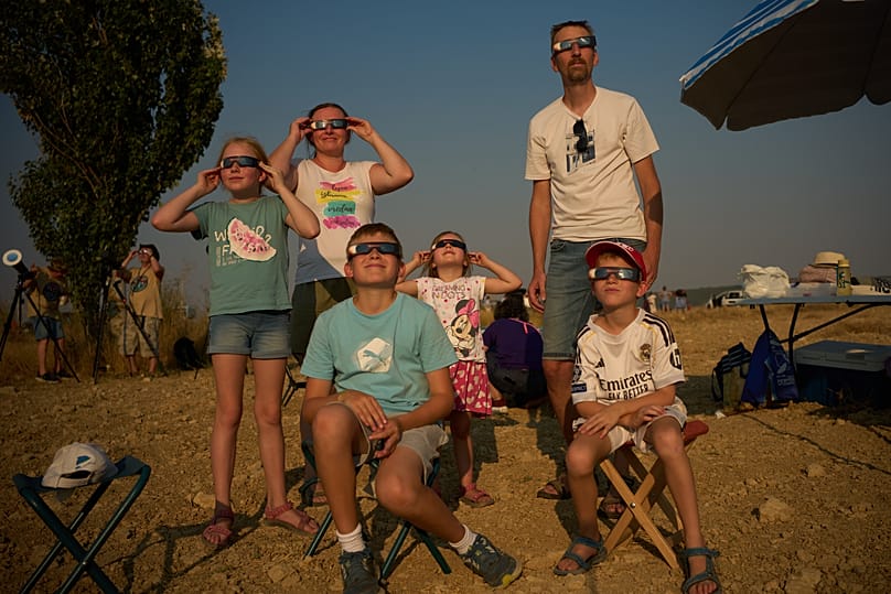 Una familia de Eslovenia observa cómo la Luna pasa por delante del Sol durante un eclipse solar total en Palencia, España, el miércoles 12 de agosto de 2026. 