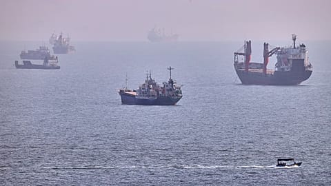 A small boat sails past cargo ships and other commercial vessels anchored in the Strait of Hormuz off Bandar Abbas, Iran, Wednesday, Aug. 5, 2026.