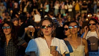 Almanya'nın Berlin kentindeki eski Tempelhof Havalimanı'nda insanlar, özel koruyucu gözlükler kullanarak güneş tutulmasını izliyor, 12 Ağustos 2026.