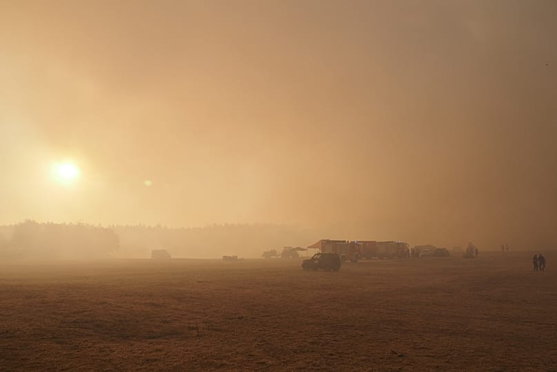 Fire trucks are engulfed in smoke from a forest fire near the hamlet of Großhau in the municipality of Hürtgenwald, Germany, at a staging area. on Friday, Aug. 14, 2026.