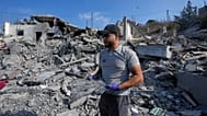 A rescue worker holds a piece of shrapnel, as he stands on the rubble of a destroyed home that was hit by an Israeli airstrike in Ansar village, southern Lebanon.