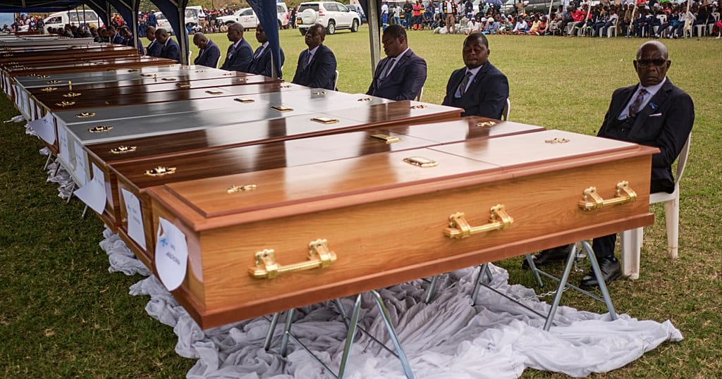 Funeral pallbearers sit behind caskets during a memorial service for the victims of a ferry that capsized on Lake Kariba in Kariba, Zimbabwe, Thursday, Aug. 13, 2026.