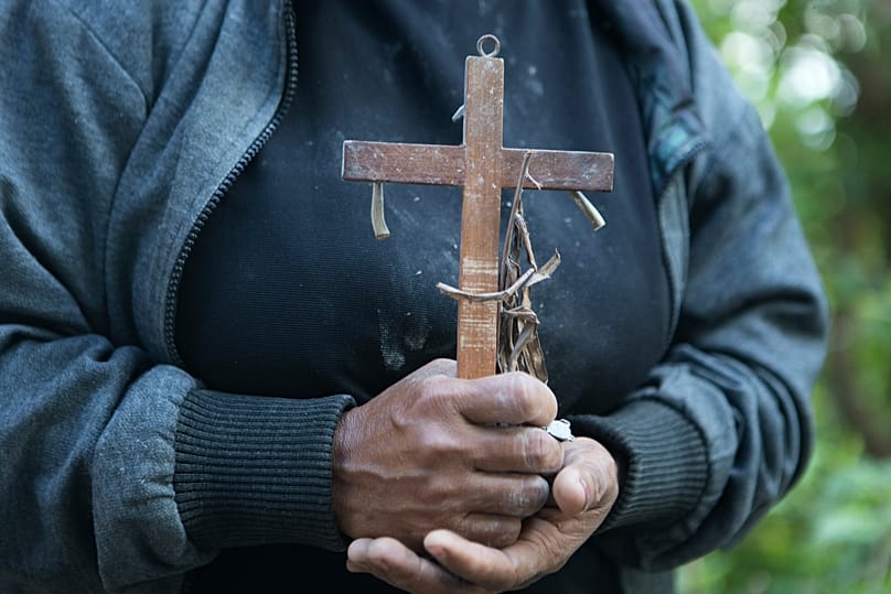 Μια γυναίκα κρατά έναν σταυρό που ανέκτησε από το ρούβλι στο σπίτι της που υπέστη ζημιές από τον σεισμό στο Mbeliling, στην επαρχία East Nusa Tenggara της Ινδονησίας