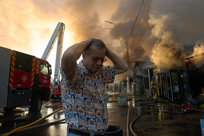 A book merchant reacts as firefighters try to put out a fire at a city book market following a Russian missile attack in Kyiv
